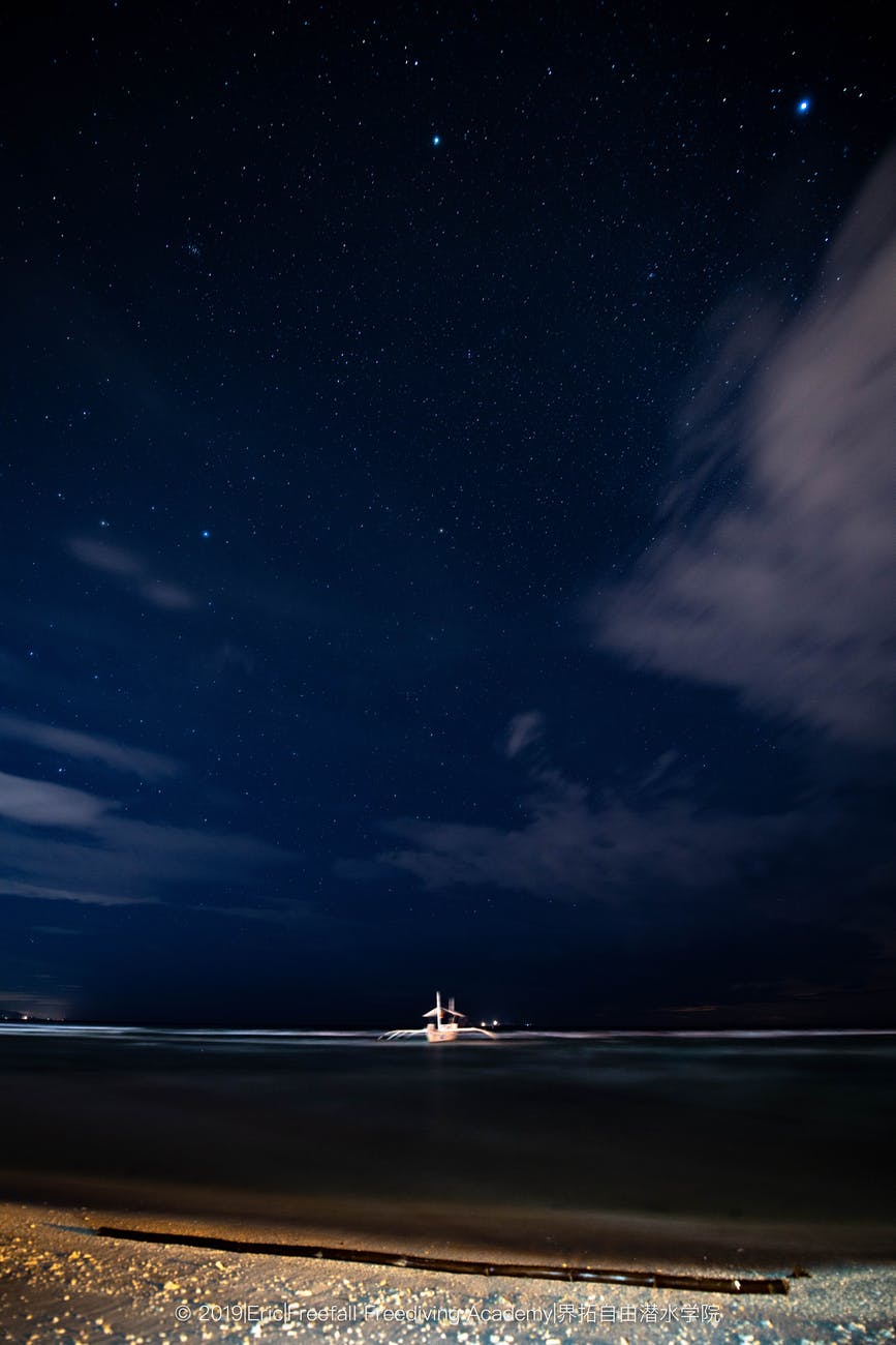 white boat on sea under blue sky during night time